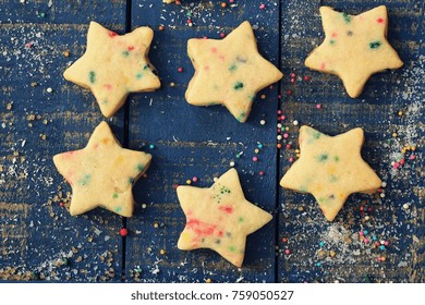 Overhead View Of Homemade Xmas Star Sugar Cookies With Colorful Sprinkles On Festive Blue Wooden Background