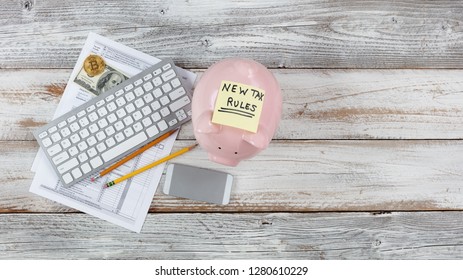 Overhead View Of Income Tax Forms With New Rule Changes And Piggy Bank On White Rustic Desk 