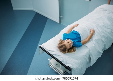 Overhead View Of Kid Lying On Medical Stretcher In Corridor