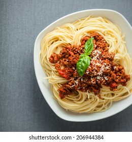 Overhead View Of A Large Bowl Of Traditional Italian Spaghetti Pasta With A Rich Tomato And Ground Beef Bolognese Topping Garnished With Fresh Basil And Parmesan Cheese