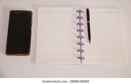 Overhead View of Lined Notebook with Purple Rings, Pen, and Smartphone