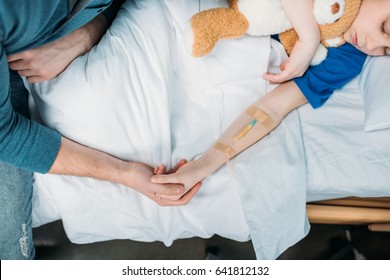 Overhead View Of Little Boy With Drop Counter Sleeping In Hospital Bed With Father Near By