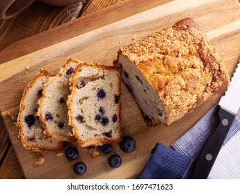 Overhead View Of A Loaf Of Sliced Blueberry Streusel Sweet Bread With Fresh Berries On A Wooden Cutting Board