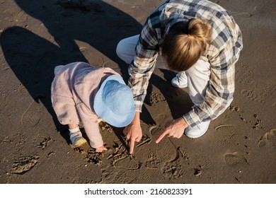 Overhead View Of Man And Baby Girl Drawing On Beach