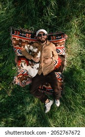 Overhead View Of A Man And Dog Resting On The Green Grass In The Summer