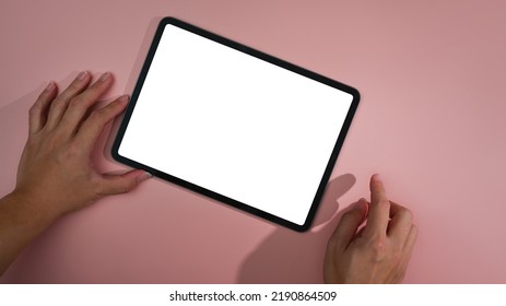 Overhead view man hands using digital tablet on pink background. Empty screen for your advertise text