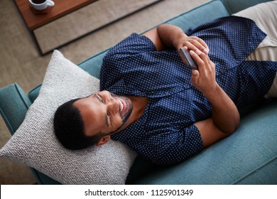 Overhead View Of Man Lying On Sofa At Home Using Mobile Phone - Powered by Shutterstock