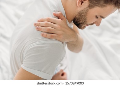 overhead view of man touching shoulder while suffering from pain