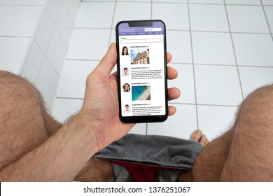 An Overhead View Of Man Using Mobile Phone In Toilet