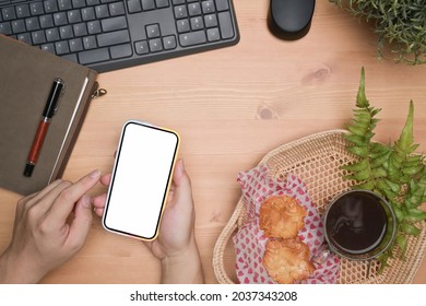 Overhead view man using mobile phone on wooden table.