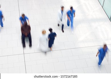 Overhead View Of Medical Staff Walking Through Lobby Of Modern Hospital Building With Motion Blur