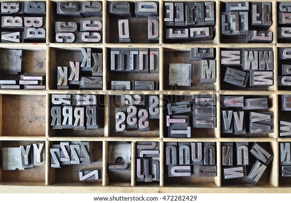 Overhead view of\
metallic letters in a wooden box, used for letterpress printing on\
a manual print machine