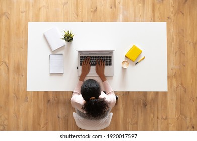 Overhead View Of Mixed-race Ethnic Woman Or Female Freelancer With Curly Hair Sitting At The White Table Desk With Well-organized Space, Typing On The Laptop, Taking Notes, Modern Home Office Concept