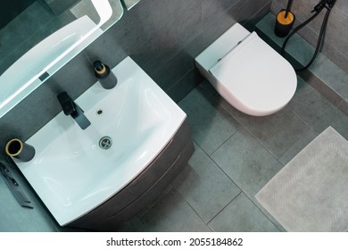 Overhead View Of A Modern Monochrome Bathroom Interior With Single White Vanity And Wall Mounted Toilet Over Grey Tiled Floor With Bathmat