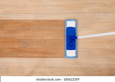 Overhead view of a modern sponge style mop being used for cleaning a wooden floor with copyspace