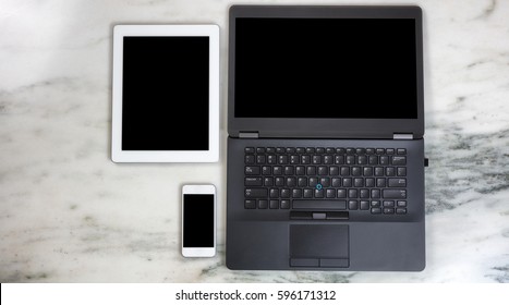 Overhead view of modern wireless mobile communication devices and computer on marble desktop. Paperless office concept.  
