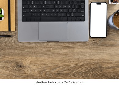 Overhead view of modern workspace featuring laptop, coffee, smartphone, documents and notebook on a wooden desk with copy space