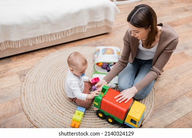 Overhead View Of Mother And Baby Son Playing With Building Blocks At Home