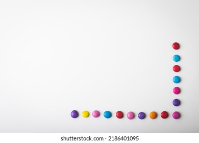 Overhead view of multi colored chocolate candies arranged by copy space over white background. unaltered, unhealthy eating and sweet food concept.