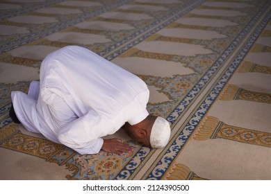 An overhead view of a Muslim man prostrate in prayer in a mosque