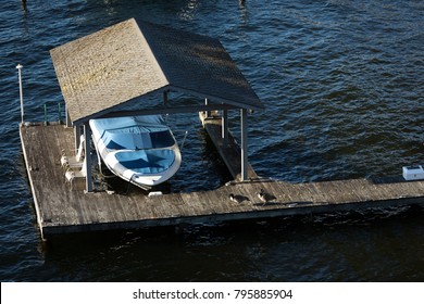 Overhead View Of An Old Boat House With A Docked Motor Boat, And Geese On The Weathered Dock, Above Calm Lake Water