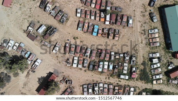 Overhead view of old cars gathered in a\
countryside parking.