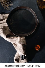 Overhead View On A Black Empty Cast Fried Iron Pan On Black Table With Spices. Dark Photography.