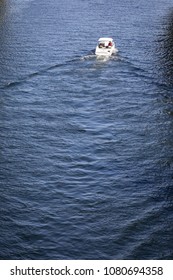 Overhead View On White Luxury Speedboat Cruising Away On A Calm Blue Lake, With Space For Text On The Bottom