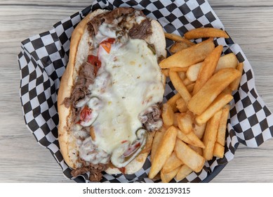 Overhead View Of Open Faced Philly Cheesesteak Sandwich Smothered In Meled Cheese Served With Steak French Fries For An Appetizing Meal.