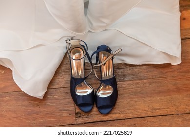 Overhead View Of The Open Toed Shoes Of The Bride Are Unbuckled And Laid Out Next To The Wedding Dress.