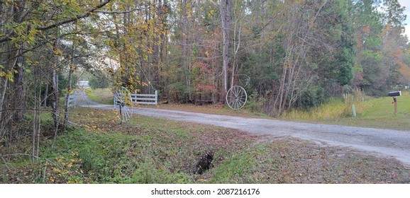 Overhead view over driveway entrance to North Florida home with antique vintage white wagon wheels white wooden fence and colorful autumn forest
