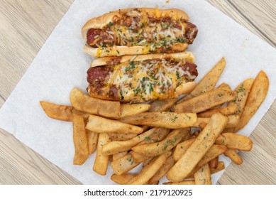 Overhead View Of Pair Of Chili Cheese Dog Hotdogs Loaded With Melted Cheese And Served With Pepper Steak Fries For A Party Appetite Hunger Meal.