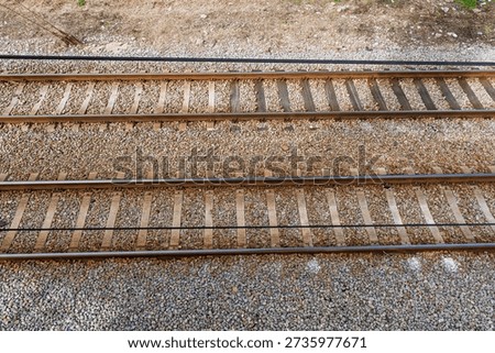 Overhead view of parallel railway tracks with steel rails and wooden sleepers on gravel ballast, outdoor transport infrastructure background.
