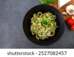 Overhead view of the pasta with pesto sauce. Tagliatelle with basil pesto Genovese and parmesan in a plate on gray stone background.