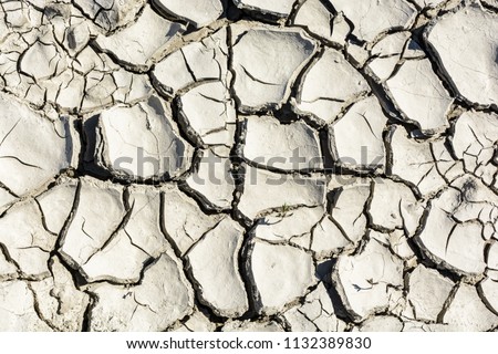 Overhead view of the patterns of a cracked dry grey earth.