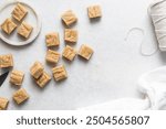 Overhead view of peanut butter fudge on a white marble tray, top view of soft peanut fudge squares on a white background