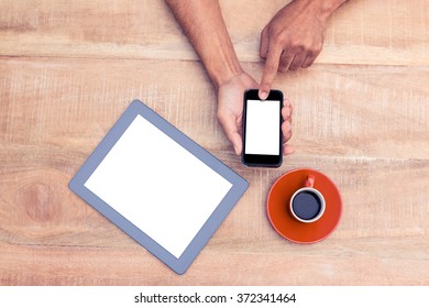 Overhead view of person using smart phone by coffee and tablet on table