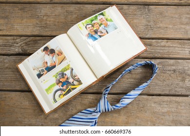 Overhead view of photo album by necktie on wooden table - Powered by Shutterstock