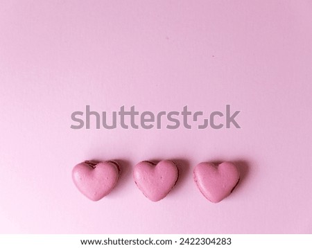 Overhead view of pink heart shaped macarons on bright pink background
