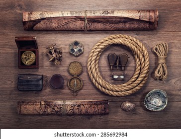 Overhead view of pirate or sailor gear laid out for a backpacking trip on a old wood floor. Items include, rope, compass, money, map, binoculars, hourglass, sextant , shell. Stories background.