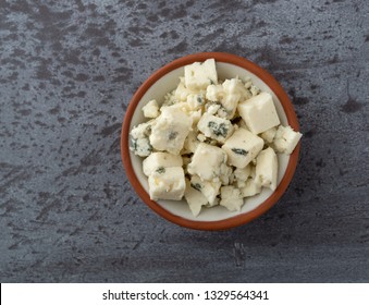 Overhead view of a portion of crumbled blue cheese in a small bowl atop a gray background illuminated with natural lighting. - Powered by Shutterstock