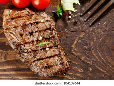 Overhead View Of A Portion Of Juicy Grilled Beef Steak With Peppercorns On A Textured Wooden Surface