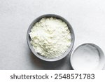 Overhead view of powdered milk in a grey bowl, top view of full fat milk powder in a bowl