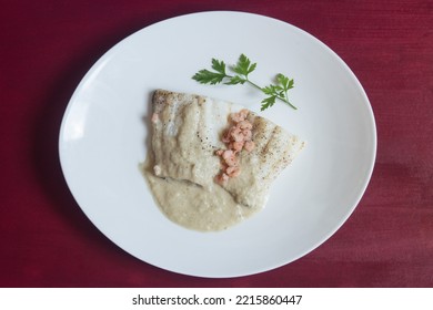 Overhead View Of A Presentation Food Plate Of Cod With Green Sauce On An Elegant Plate Garnished With A Sprig Of Fresh Parsley On A Table With Red Painted Wood Texture. Healthy White Fish Recipe.