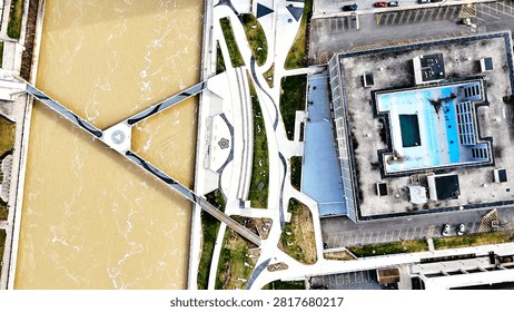 An overhead view of the promenade and multiple pathways and public spaces that are situated next to the river that flows through the center of this city.