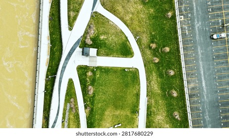 An overhead view of the promenade and multiple pathways and public spaces that are situated next to the river that flows through the center of this city.
