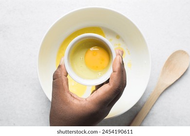Overhead view of raw egg in a ceramic ramekin, whole raw egg in a white ramekin