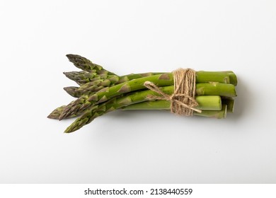 Overhead view of raw green asparagus tied with string by copy space on white background. unaltered, food, healthy eating and organic concept.