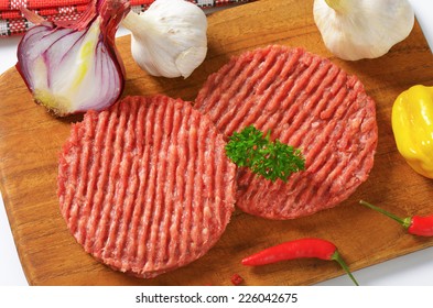 Overhead View Of Raw Minced Beef Burger With Fresh Onion, On The Wooden Cutting Board