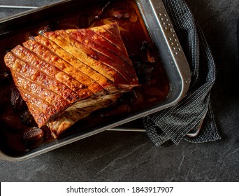 Overhead view of roasted pork belly with crust on a baking tray